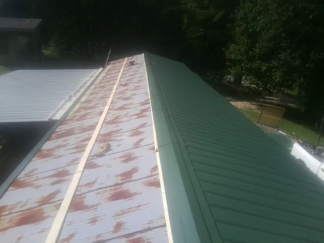 Old rusted panels beside newly installed green metal roofing — Wind Damage Roof Repair by Roofing Brothers in Sewaren
