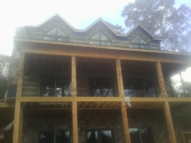Dormers and porch framing on a large log home under construction — Roof Coating work by our crew in Sewaren