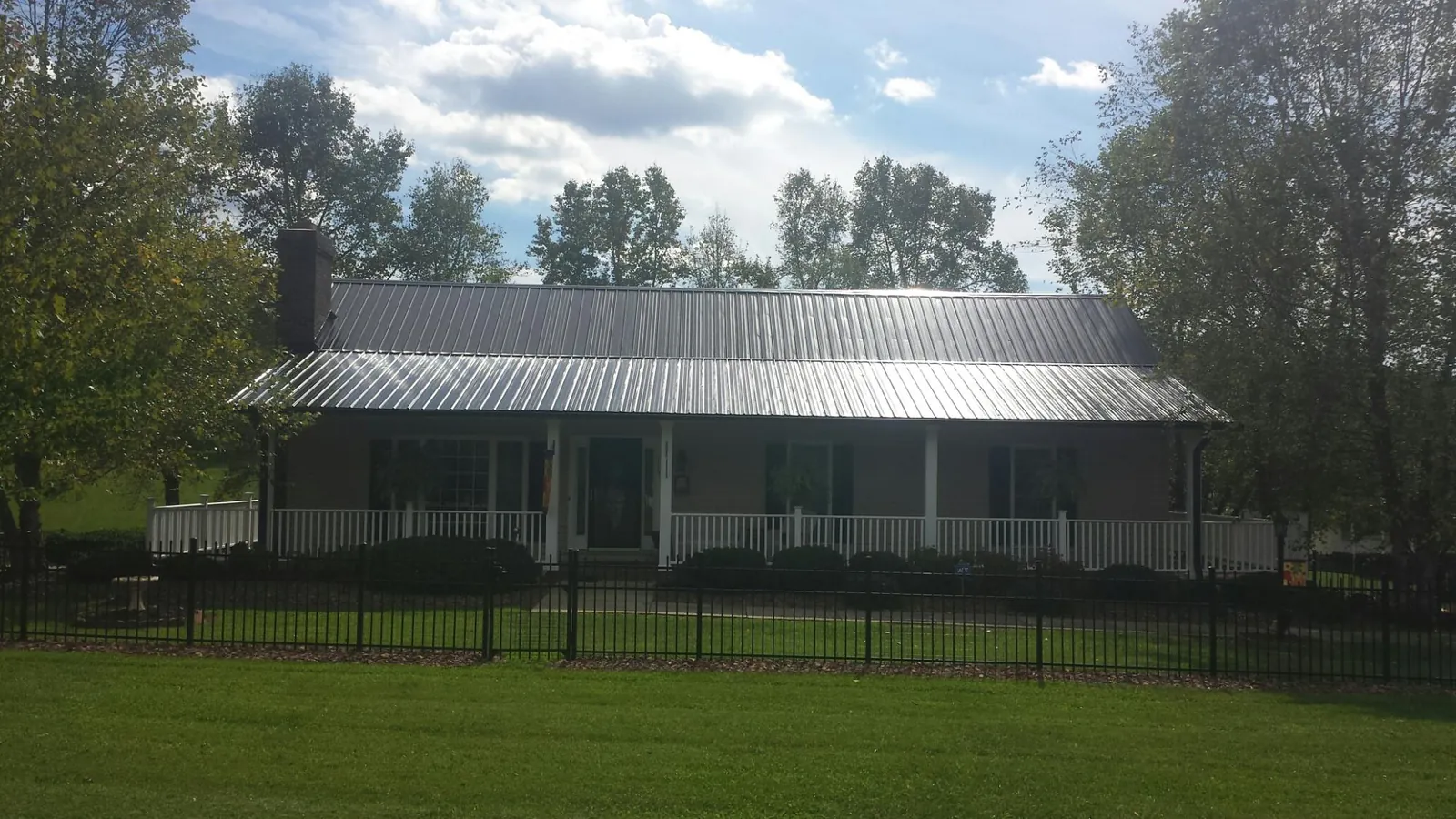 Gray metal roof on a brick ranch with a full width front porch — Gutter Guard Installation work by our crew in Sewaren