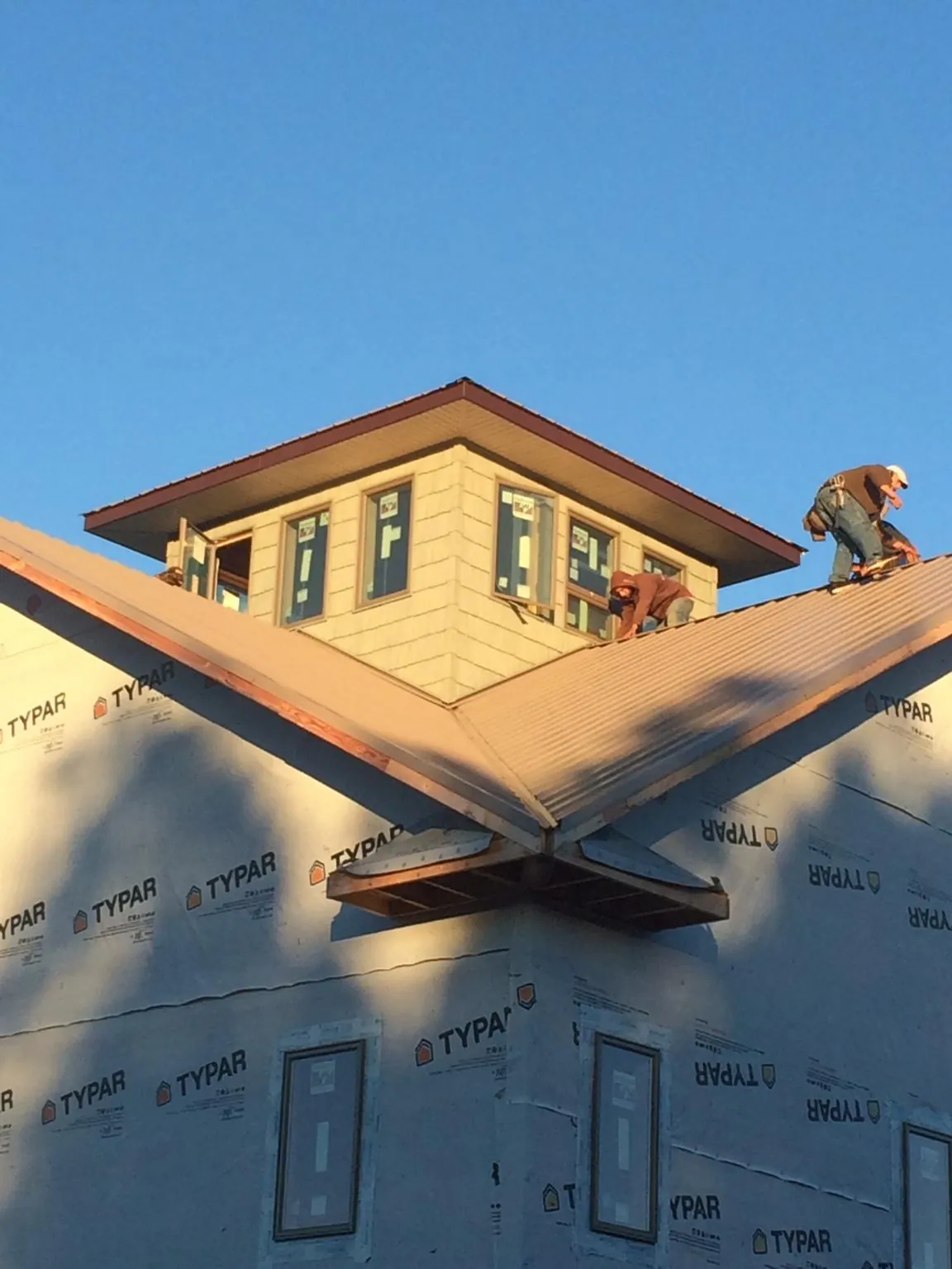Roofers working around a rooftop cupola on a new metal roof at sunset — Roof Waterproofing in Sewaren by Roofing Brothers